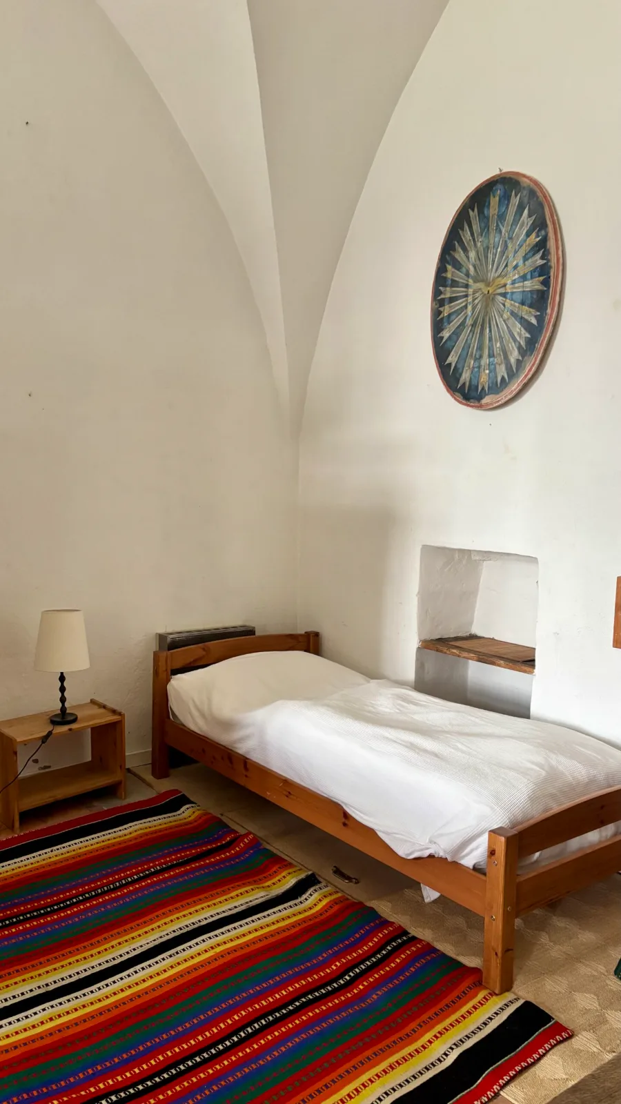 Chambre simple avec lit et couverture colorée au domaine de la retraite