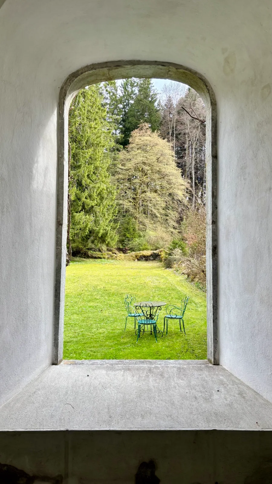 Vue sur le jardin à travers une arche de pierre du domaine